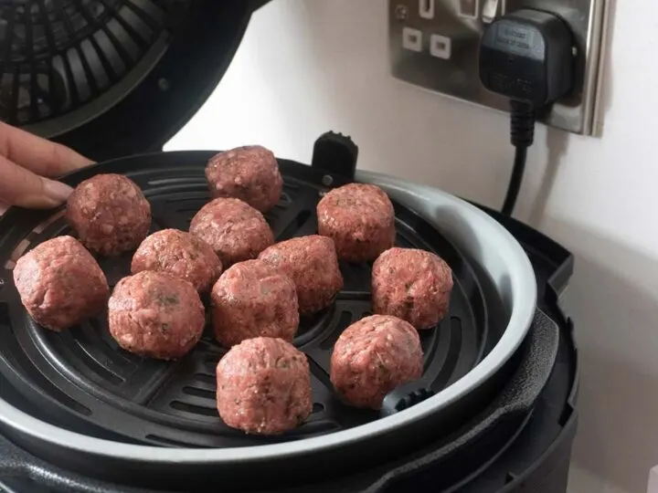 Raw Meatballs Being Placed Into An Air fryer