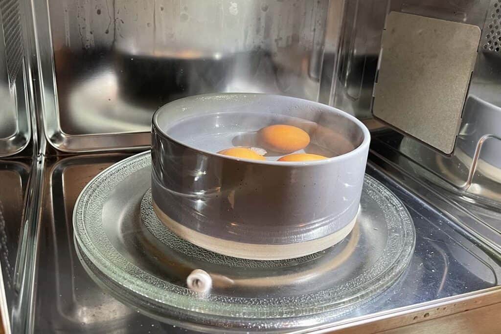 3 Eggs Being Cooked in A Bowl In The Microwave